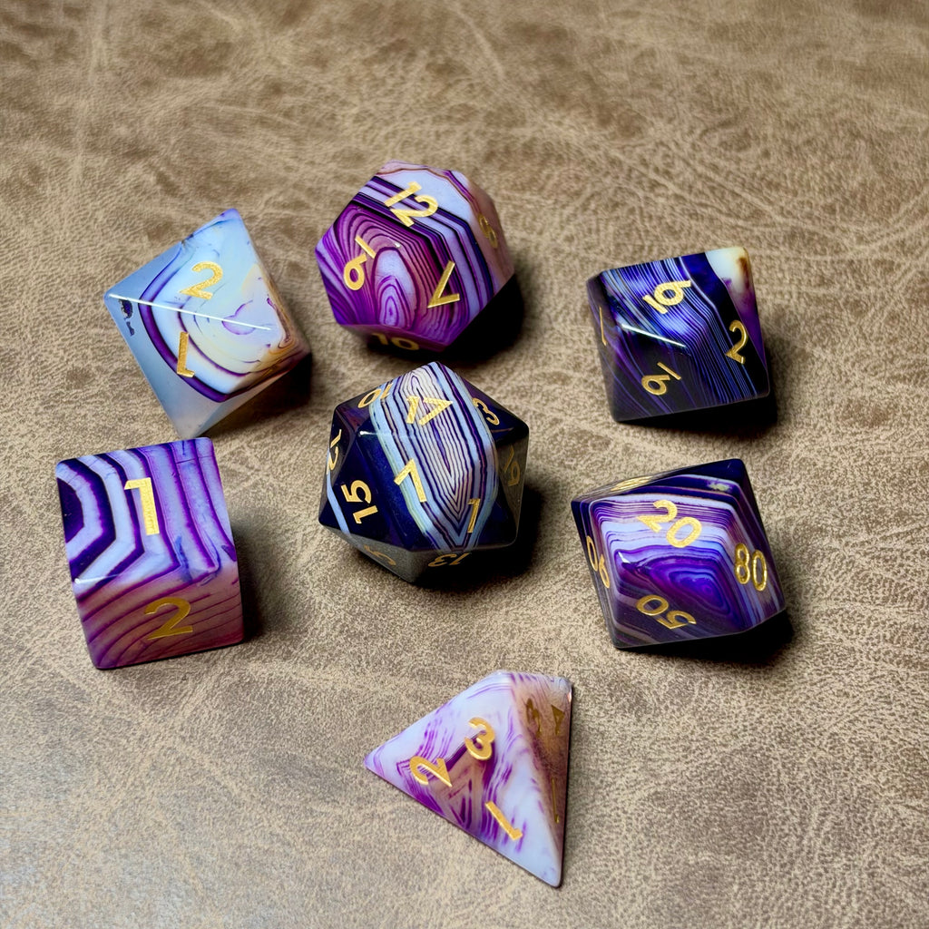 Violet Strata natural stone polyhedral dice set with deep violet striping and gold numbers